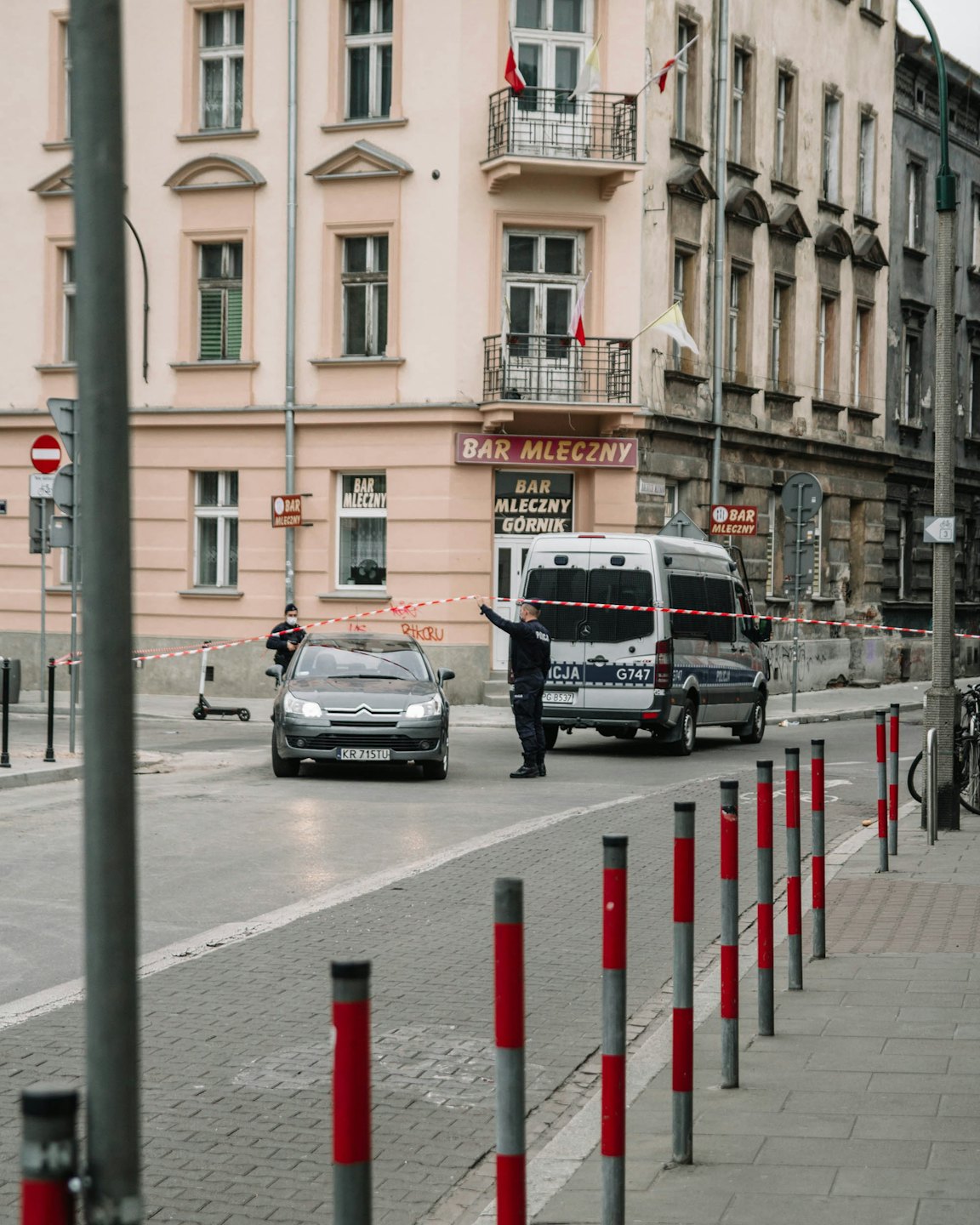 Rendőr rendőrszalagot tart egy városi utcában.
